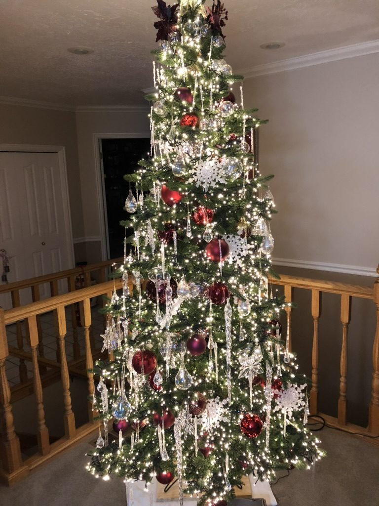 Tall decorated indoor tree with white lights, red ornaments and icicles
