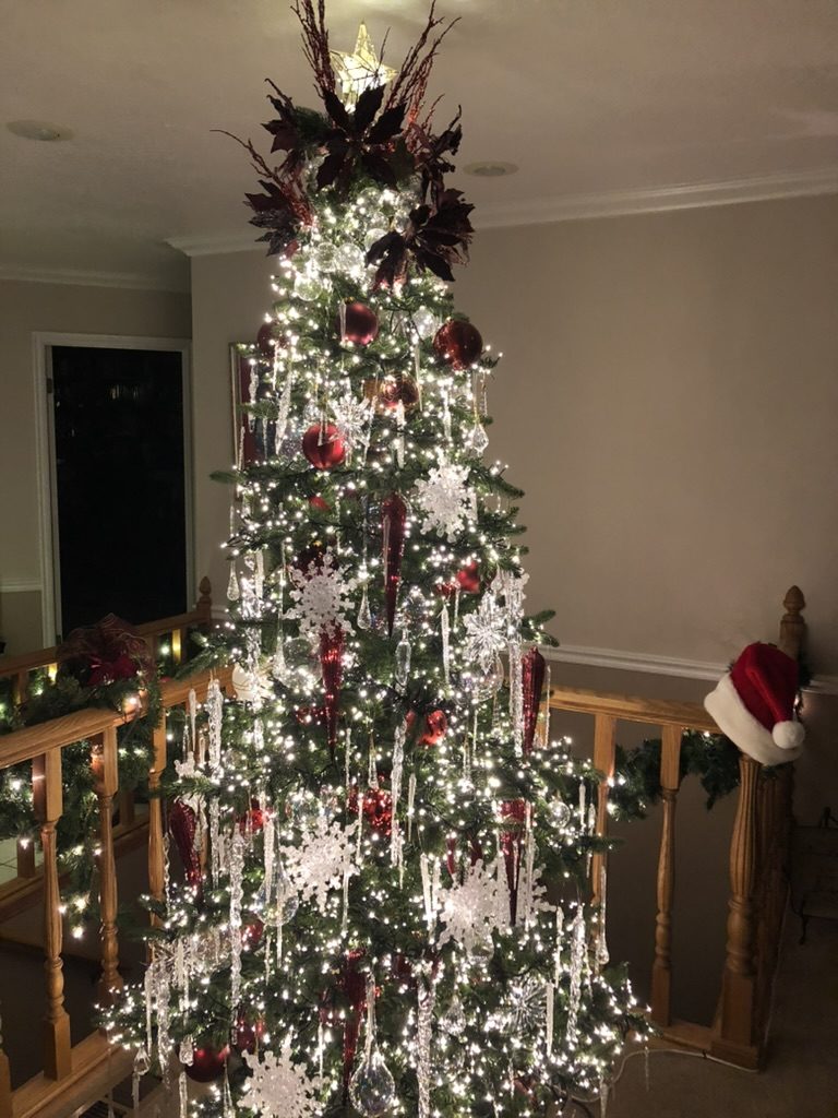 Tall indoor Christmas tree with white lights, red ornaments, glass icicles and snowflakes